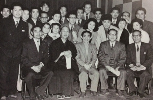 1957年、電通ラジオテレビ局時代に「エノケン・がんばれ人生」の出演者・スタッフらと(前列左端)